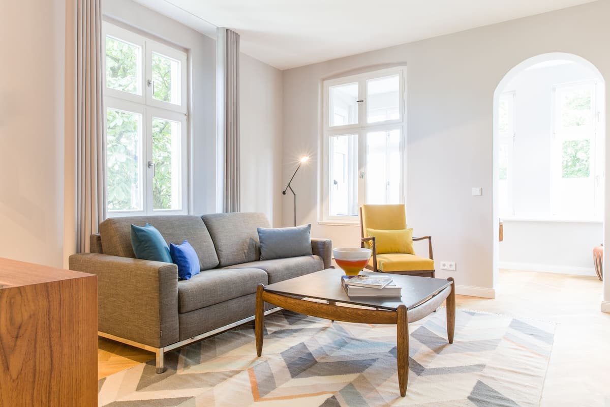 Un salon moderne avec un canapé gris, un fauteuil jaune et une table basse.