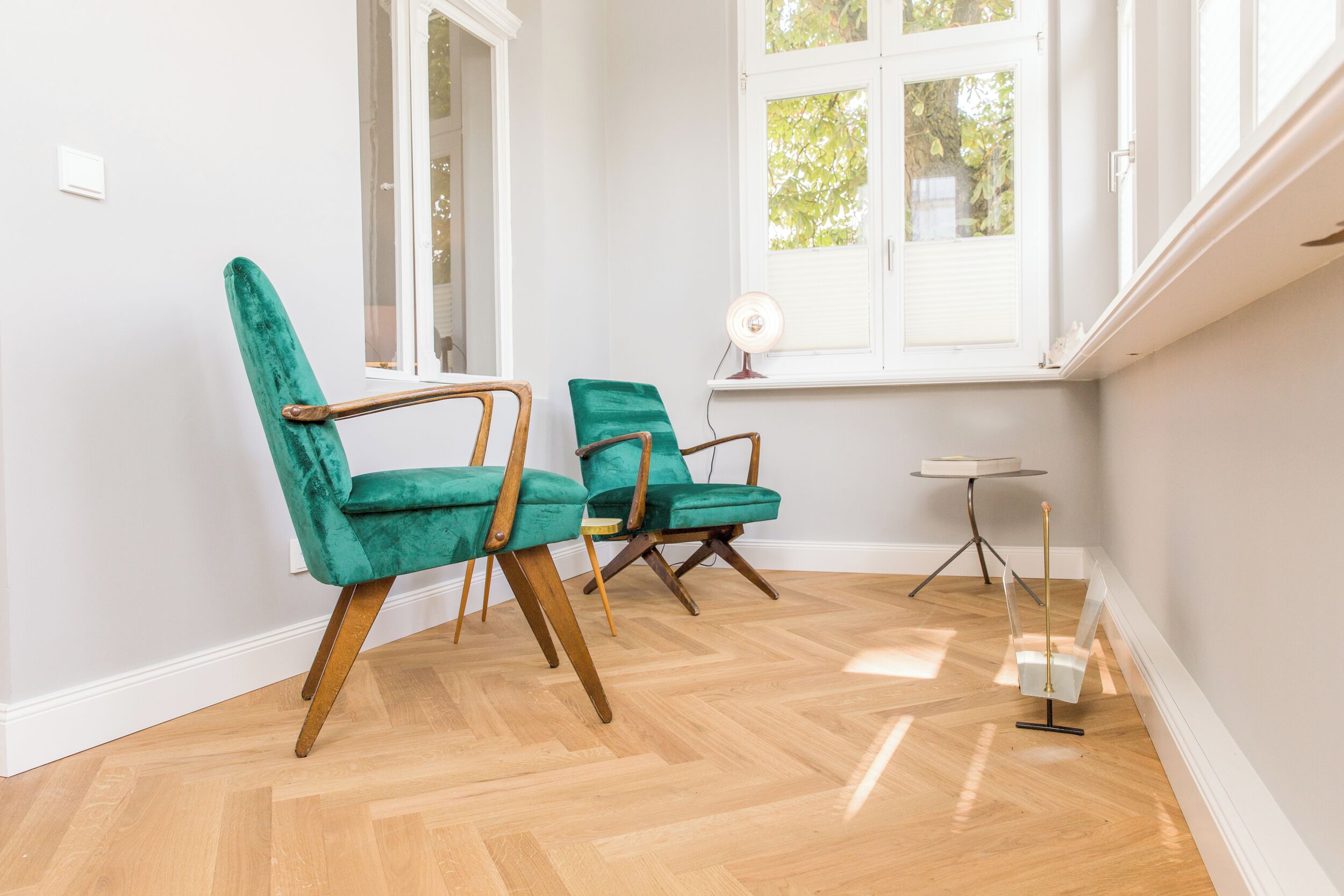 A room with two teal chairs, a small round table, and a floor lamp.