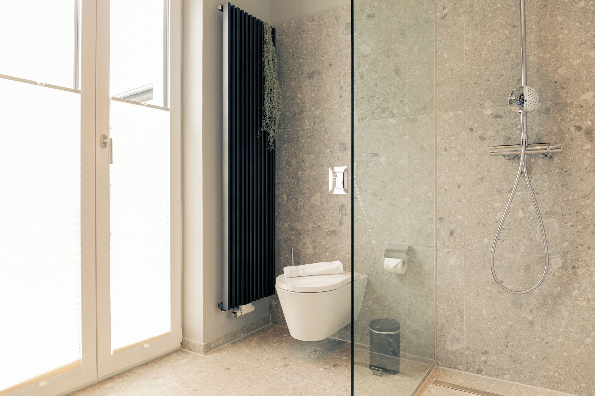 Ein modernes Badezimmer mit Duschkabine, Toilette und Handtuchheizkörper.