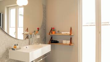 A bathroom with a white sink, a mirror, and wooden shelves with toiletries.