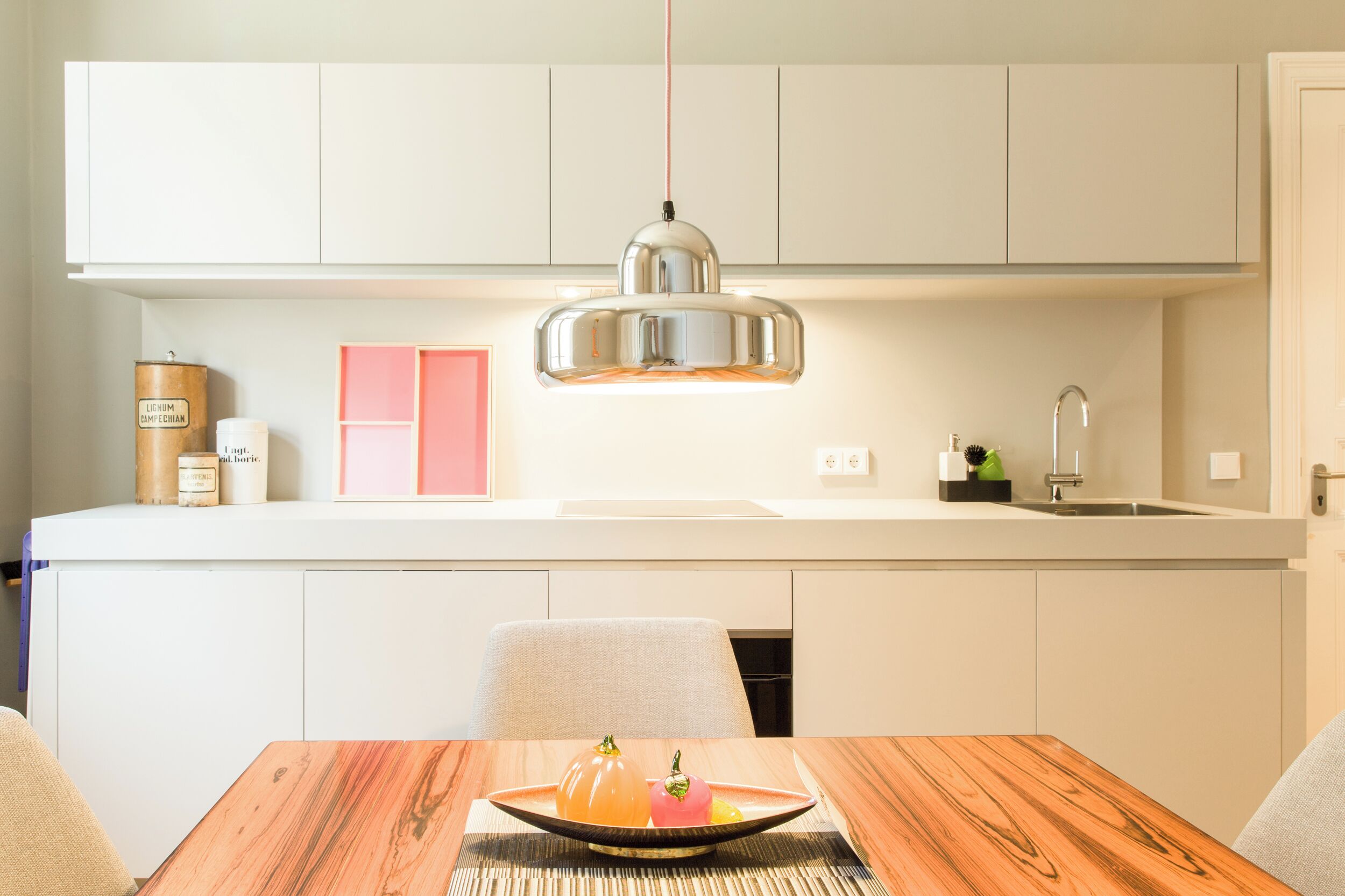 A modern kitchen with white cabinets, a central island, and a hanging pendant light.
