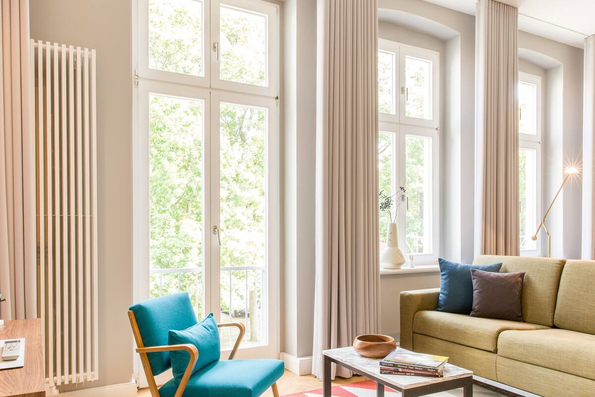 Un salon bien éclairé, avec un canapé, un fauteuil, une table basse et un radiateur.