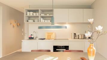 Una cocina moderna con gabinetes blancos, una isla central y una mesa de comedor con un libro y una banana.