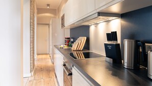 A modern kitchen with a black countertop, stainless steel appliances, and wooden cutting boards. - OSTKÜSTE - Villa Albatros Design Apartments (Heringsdorf)