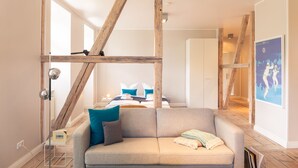 A modern living room with exposed wooden beams, a grey sofa with cushions, and a framed picture on the wall. - OSTKÜSTE - Villa Albatros Design Apartments (Heringsdorf)