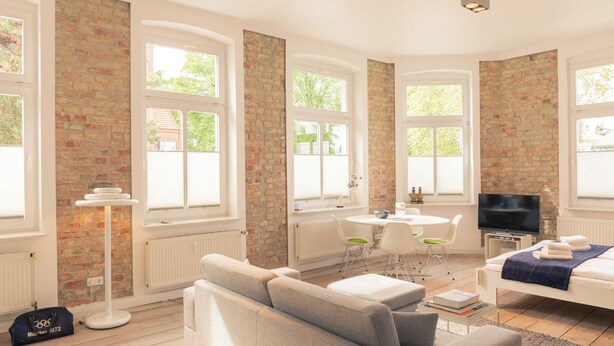 A modern living room with a sofa, a TV, and a dining area with a table and chairs. - OSTKÜSTE - Villa Albatros Design Apartments (Heringsdorf)