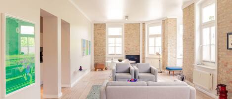 Ein geräumiges Wohnzimmer mit einem großen grauen Sofa, einem Fernseher und einer Wand aus Steinziegeln.