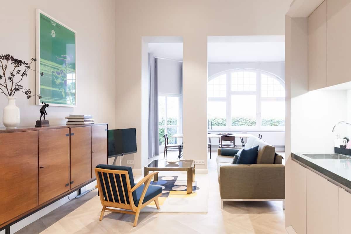 A modern living room with a wooden cabinet, a TV, a sofa, and a dining area with a table and chairs.