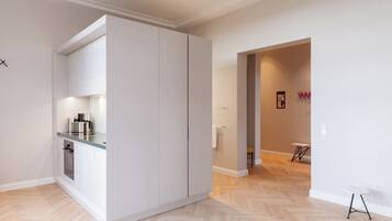 A modern kitchen with white cabinets, a stainless steel countertop, and a built-in oven.