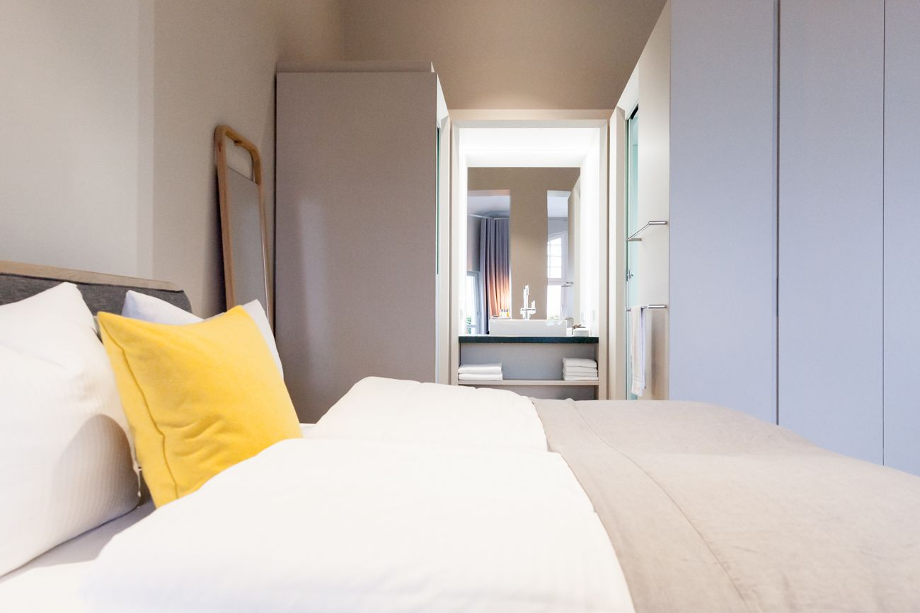 Una habitació d'hotel amb un llit, una tauleta de nit, un mirall i un armari.