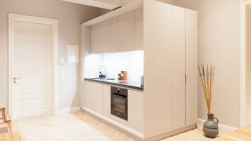 A modern kitchen with built-in appliances, a wooden floor, and a vase with reeds.