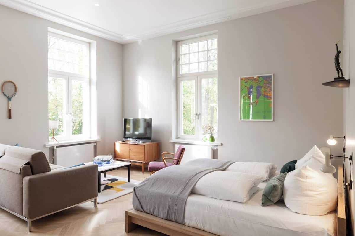 A modern bedroom with a bed, a sofa, a TV, and a desk.