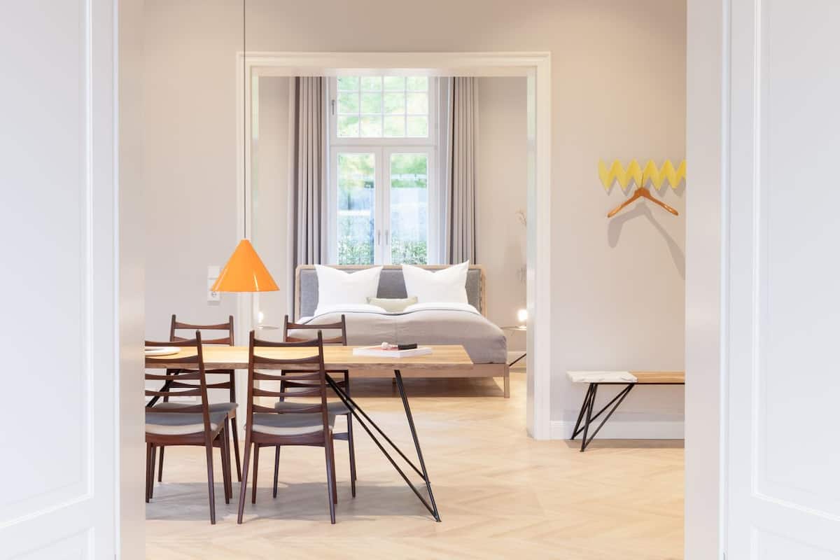 A modern bedroom with a bed, a bedside table, a chair, and a window with curtains.