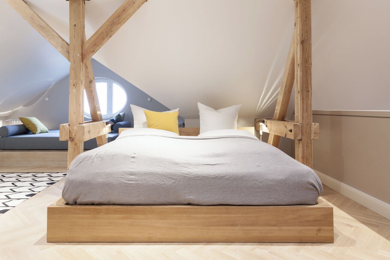 Een slaapkamer met een houten bedframe, een grijze matras en een houten hoofdbord.