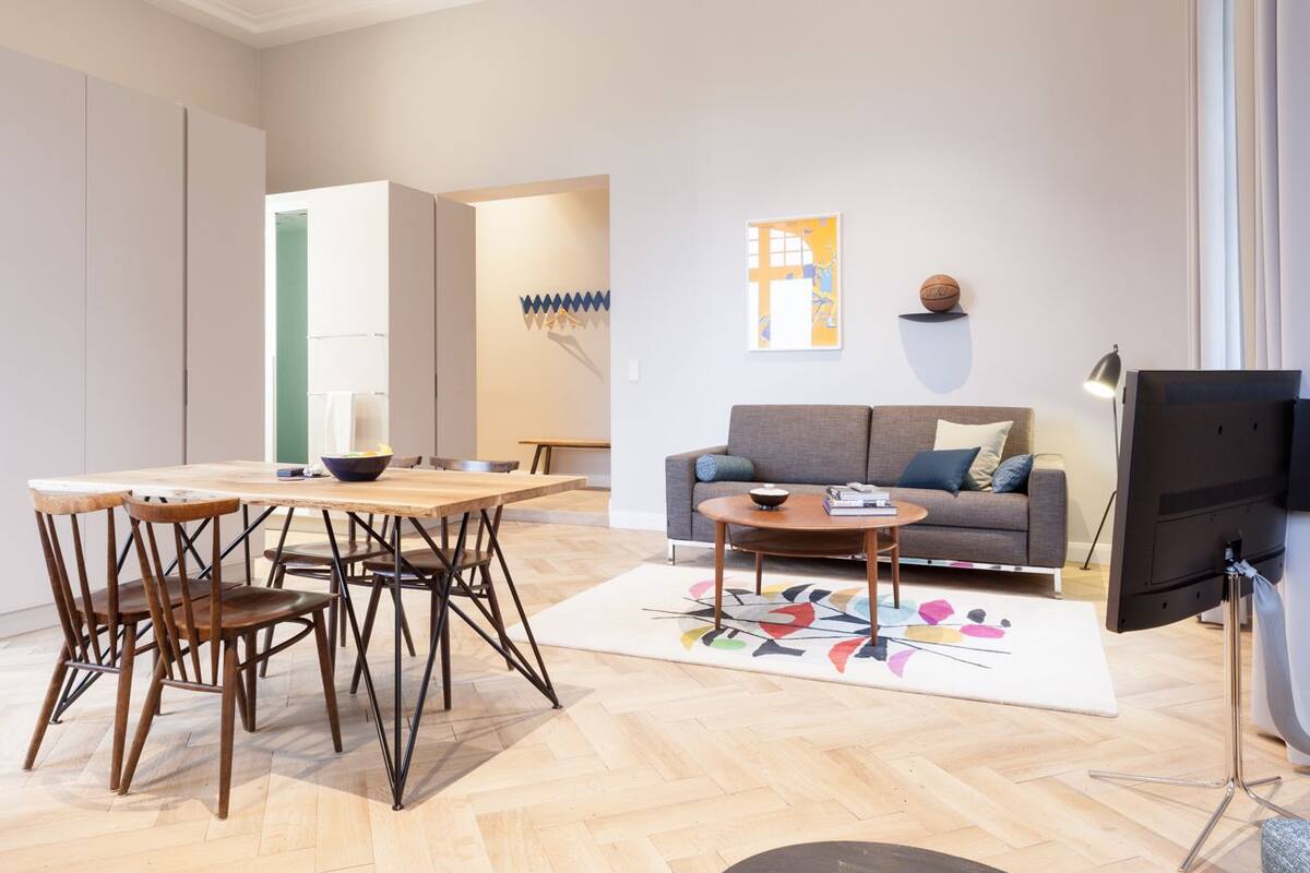 A living room with a sofa, coffee table, and TV. There is a dining area with chairs and a table.