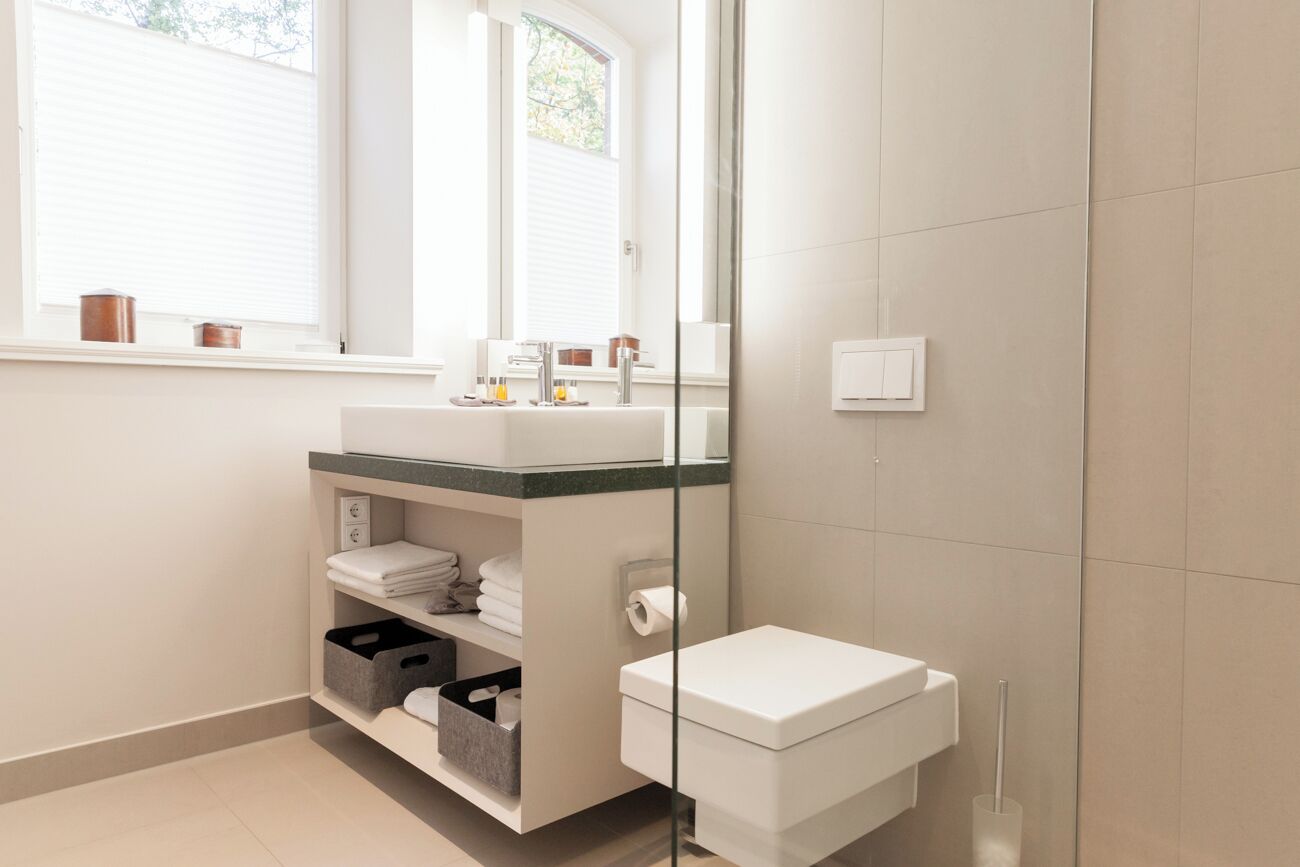 Un bagno moderno con box doccia in vetro, lavabo bianco e piano d'appoggio verde, e un water.