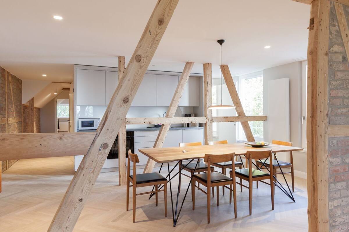 A modern kitchen with white cabinets and a wooden dining table with chairs.