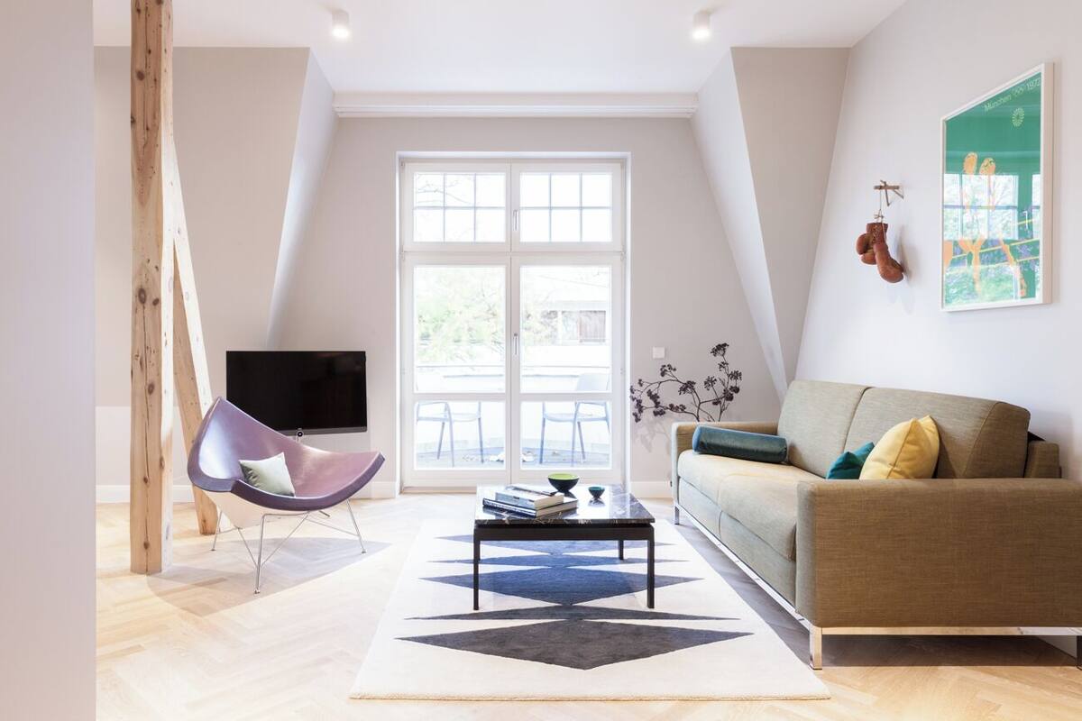 A modern living room with a sofa, a chair, a coffee table, and a TV.