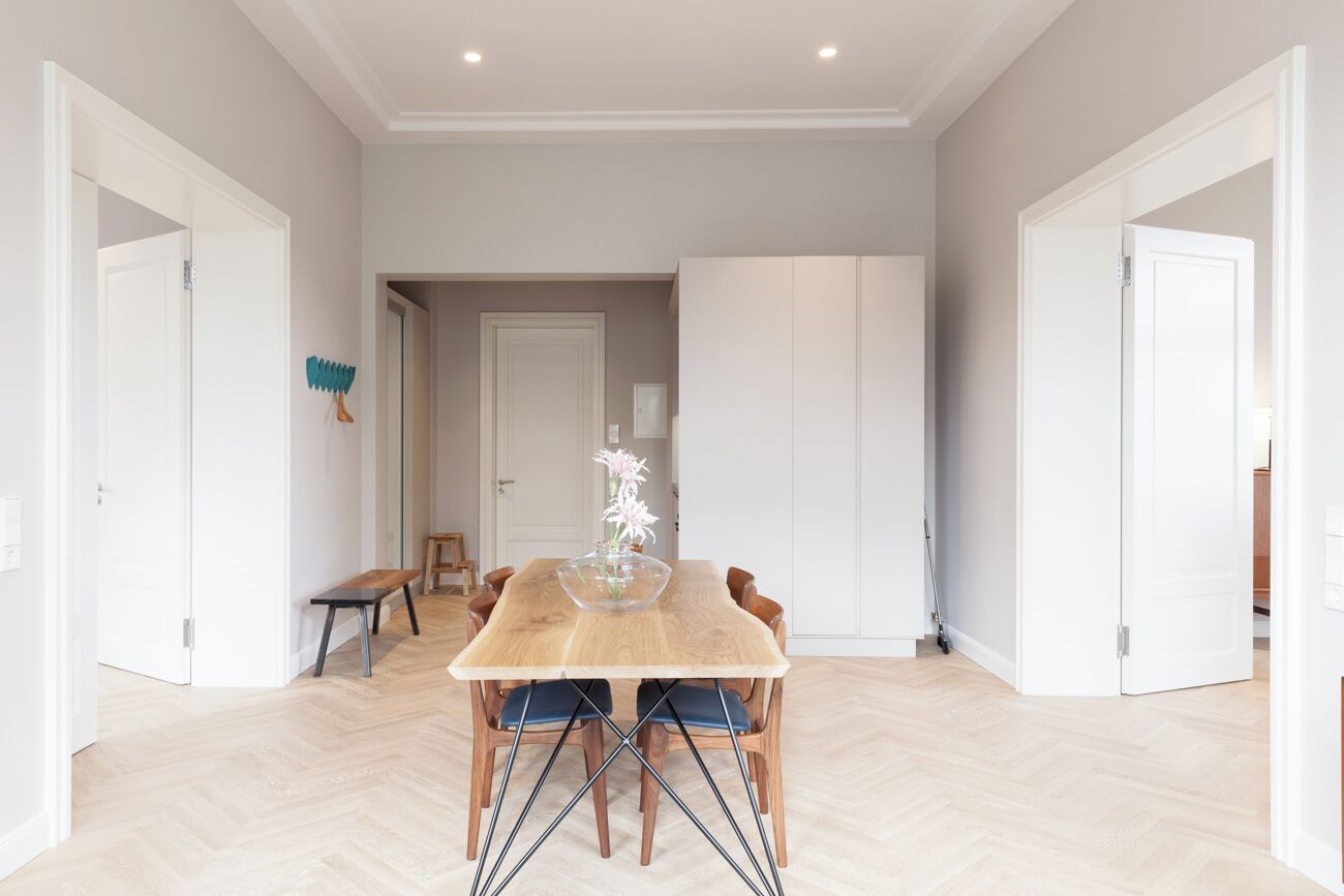 Een eetruimte met een houten tafel, blauwe stoelen en een vaas met bloemen.