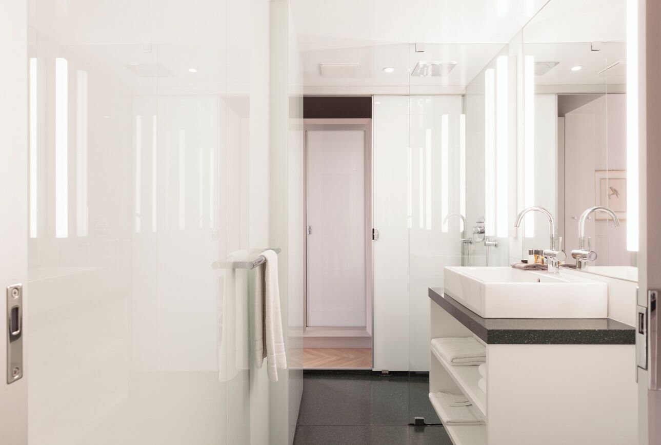 A modern bathroom with a large mirror, a white sink, and a towel rack.