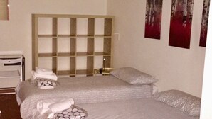 A hotel room with two beds, a headboard, a bedside table, and a wall-mounted artwork. - Pitti Four (Florence)