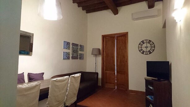 A living room with a sofa, a TV, a clock, and patterned wall art. - Pitti Four (Florence)