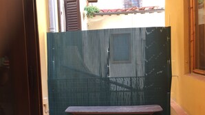 A narrow alleyway with a wooden bench and a green fence. - Pitti Four (Florence)