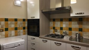 A kitchen with a stove, oven, and a washing machine. - Pitti Four (Florence)