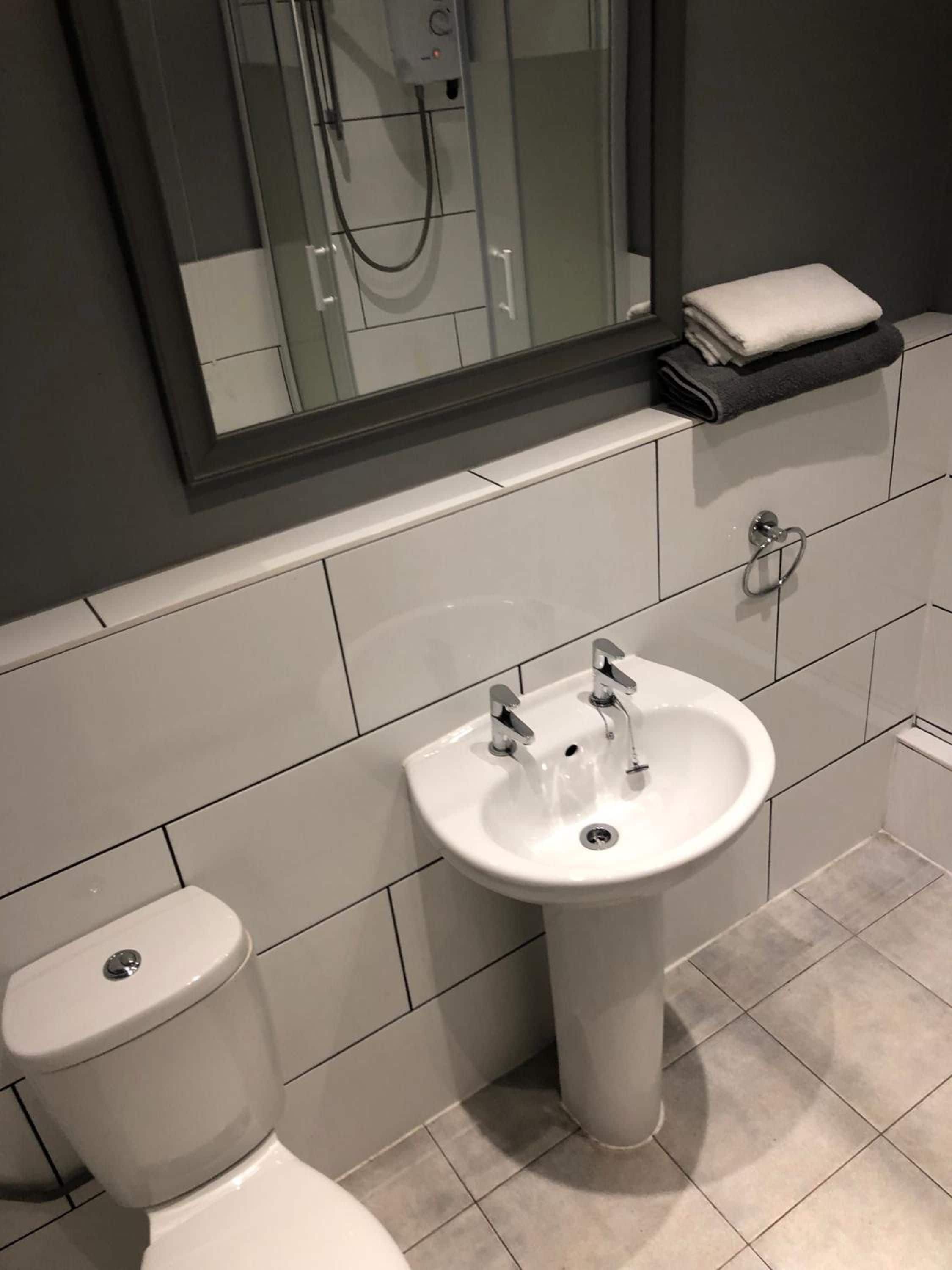 Un baño con un lavamanos blanco, un inodoro y un espejo sobre el lavamanos.