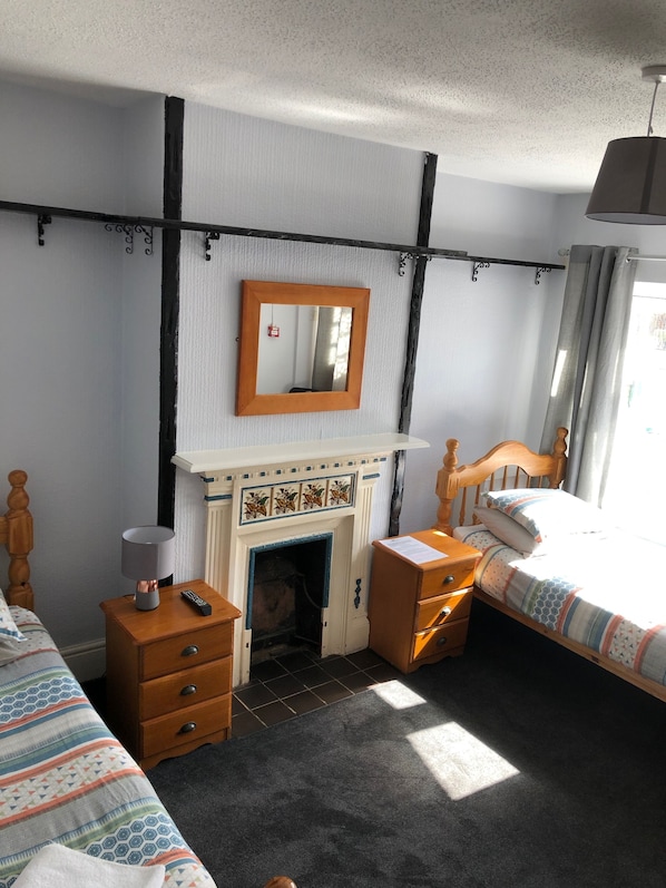 Un dormitorio con chimenea, una cama, una mesita de noche, un aparador y un espejo.