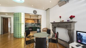 A modern interior with a round glass table, black chairs, a stone fireplace, and a television on a white stand. - Vigna Nuova (Florence)