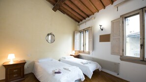 A room with two beds, a nightstand, a mirror, and a window with shutters. - Vigna Nuova (Florence)