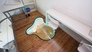 A room with a wooden floor, a white desk, a white chair, and a glass table. - Vigna Nuova (Florence)