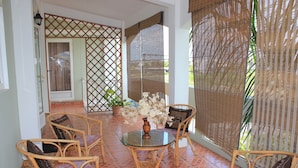 A room with a glass table surrounded by wicker chairs, a potted plant, and a decorative vase. - LeBovallon B&B (Mahebourg)