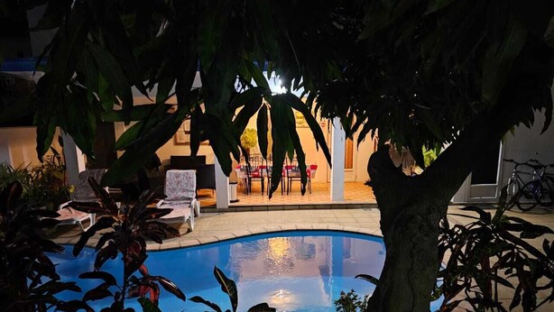 A swimming pool surrounded by lounge chairs and a dining area with tables and chairs. - LeBovallon B&B (Mahebourg)
