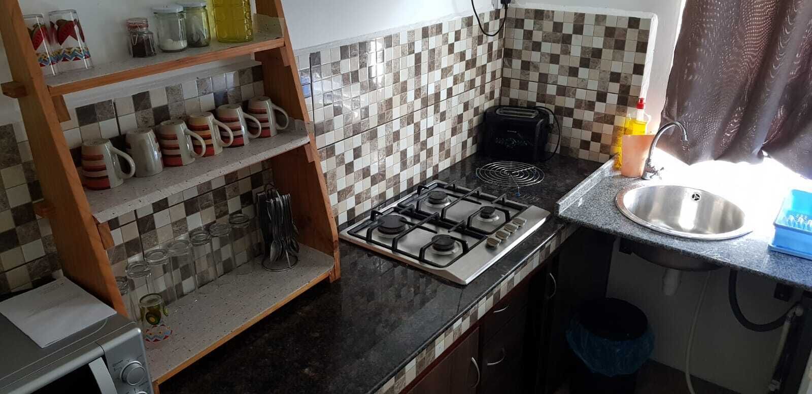 A kitchen with a gas stove, a toaster, and various kitchen items on shelves.