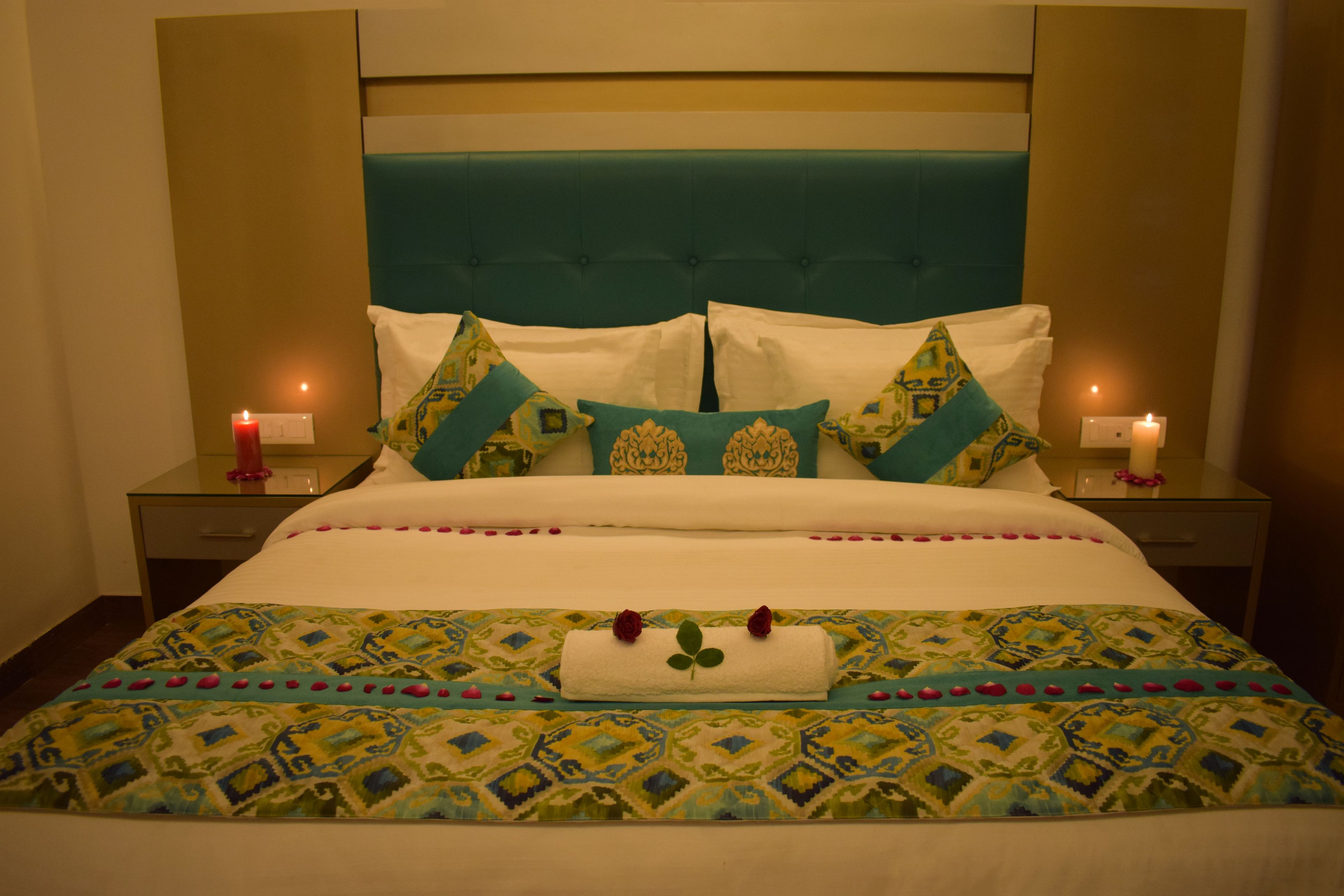 Un lit bien fait, avec une couvre-lit à motifs, deux oreillers et une serviette décorative ornée de fleurs.
