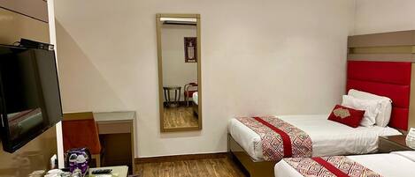 A hotel room with two beds, a TV, a desk with a chair, and a mirror.