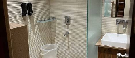 Une salle de bain moderne avec une douche à parois de verre, des toilettes blanches et un lavabo doté d’un plan de travail en bois.