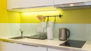 A modern kitchen with a stainless steel sink, a kettle, and utensils hanging on a rack. - MirÓ Studio apartments Zagreb (Zagreb)