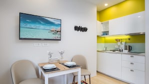 A compact living space with a dining area, a kitchen, and a large TV mounted on the wall. - MirÓ Studio apartments Zagreb (Zagreb)