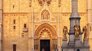A cathedral with a large arched entrance, statues, and a tall column. - MirÓ Studio apartments Zagreb (Zagreb)