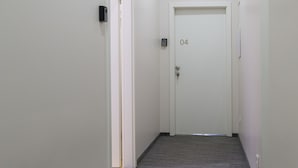 A narrow hallway with carpeted floors and white walls, leading to a door marked with the number 04. - MirÓ Studio apartments Zagreb (Zagreb)