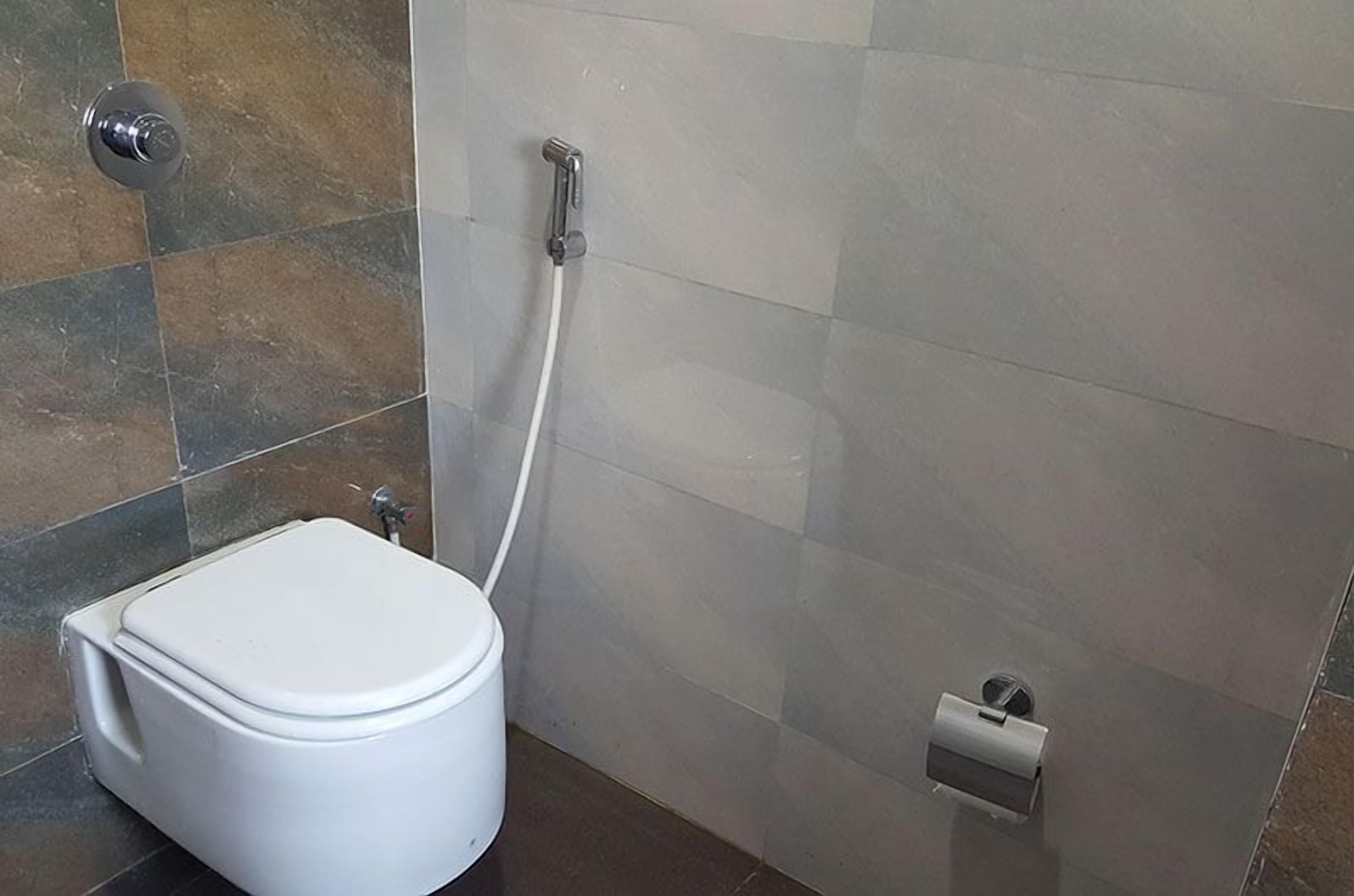 A bathroom with a toilet, a shower, and a toilet paper holder.