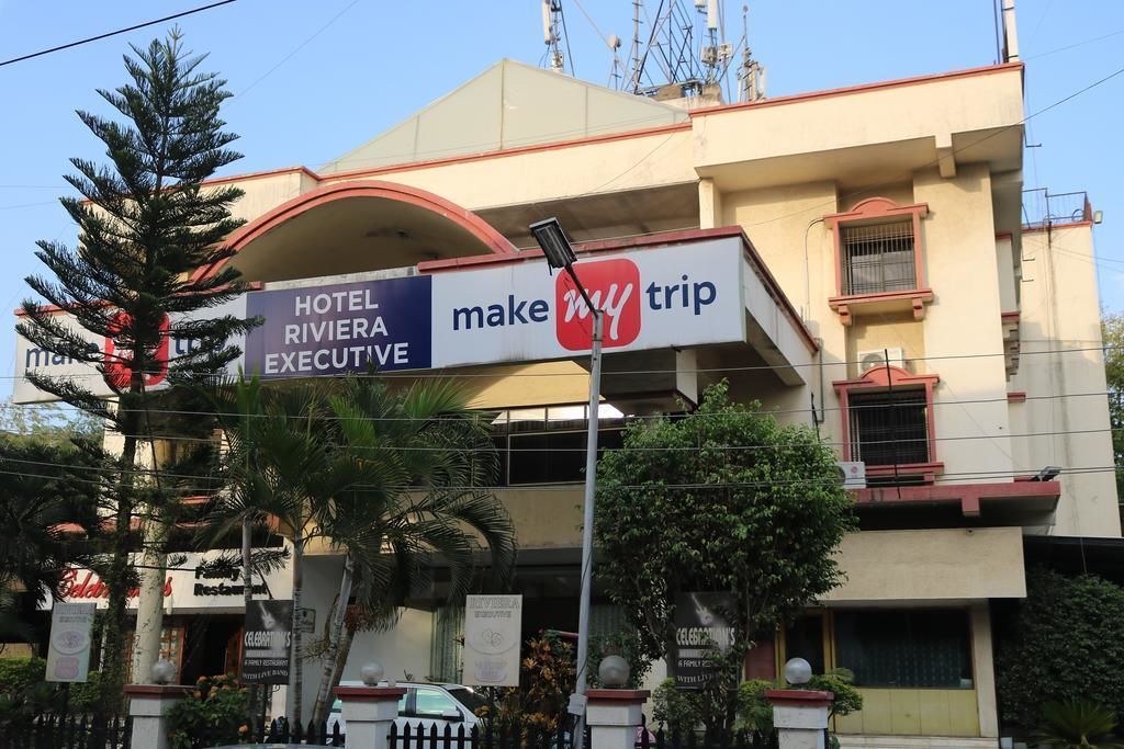 A hotel named 'Hotel Riviera Executive' with a 'Make My Trip' sign.