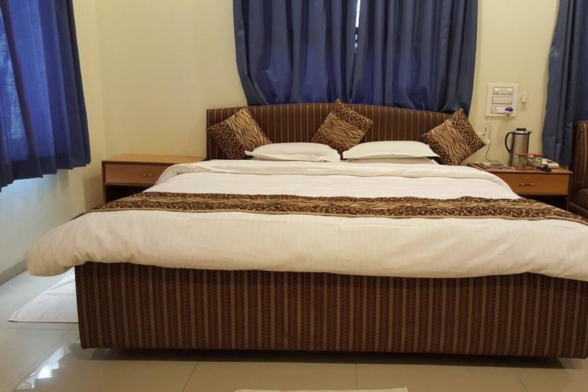 Una cama grande con cabecera a rayas, dos mesitas de noche y una silla.