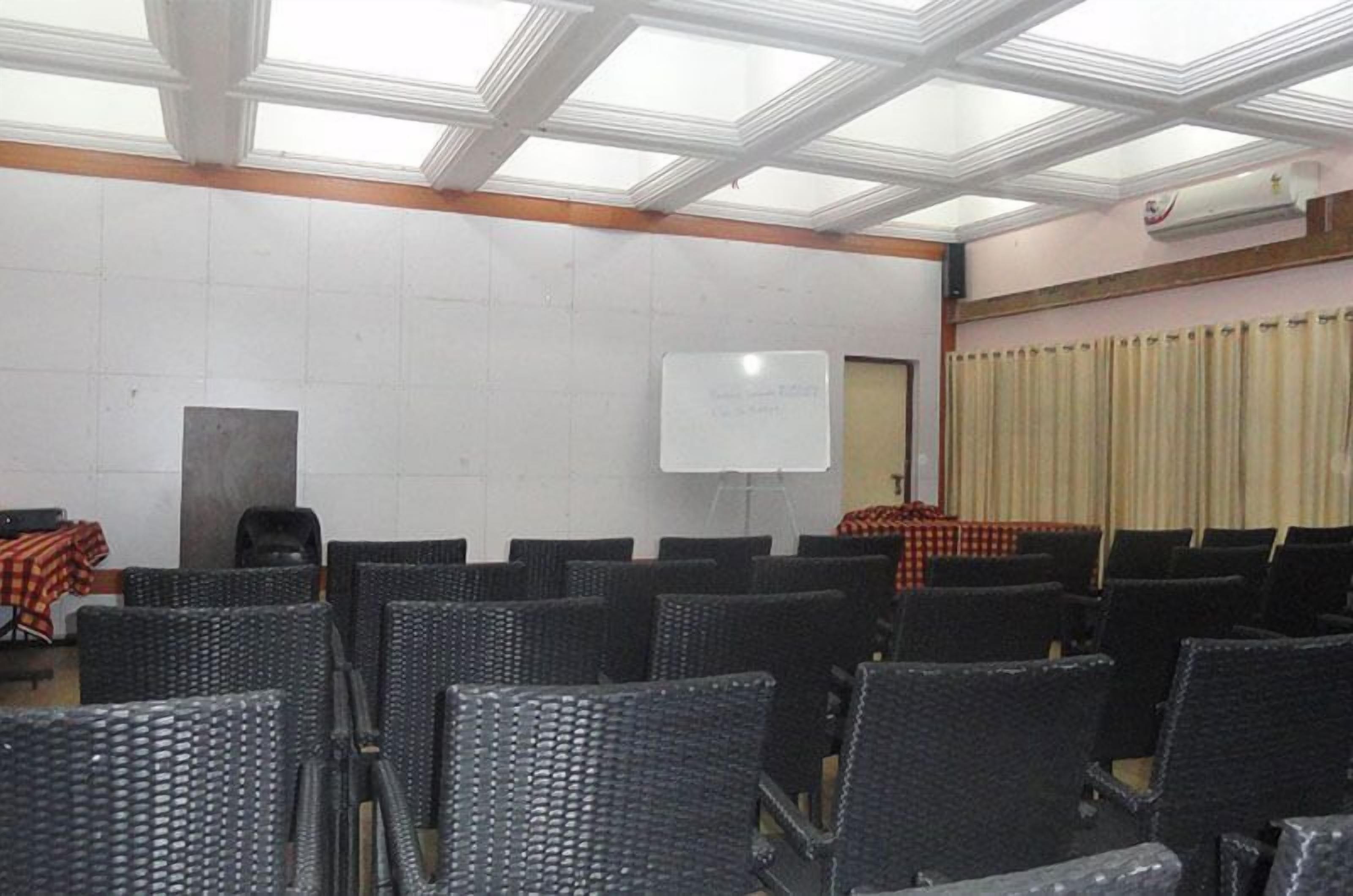 Ein Konferenzraum mit schwarzen Stühlen, einer Whiteboard und einem Tisch mit kariertem Tischleinentuch.
