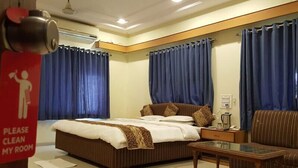 A hotel room with a bed, a nightstand, a coffee table, and a sofa. - Hotel Riviera Executive (Chhatrapati Sambhajinagar)