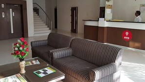 A hotel lobby with a reception desk, a staircase, and a sofa area. - Hotel Riviera Executive (Chhatrapati Sambhajinagar)