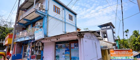 A two-story building with a blue and white facade, featuring a balcony on the upper floor.